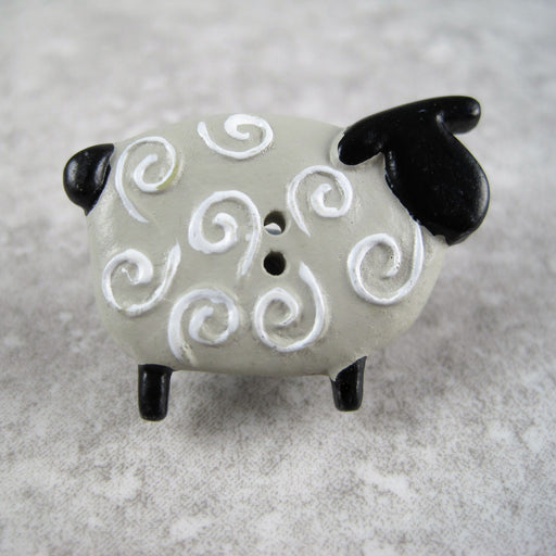 Sheep button with black head and tail.